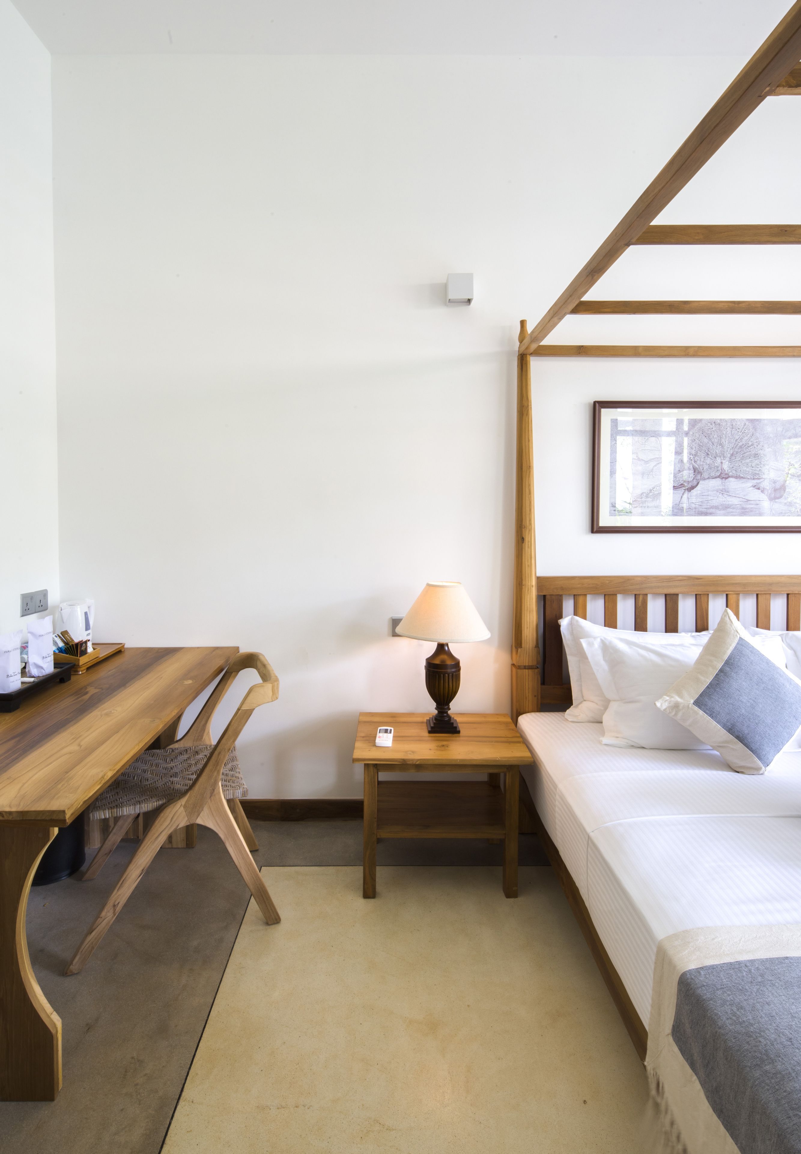 Ein Zimmer mit einem hölzernen Bett, einem Nachttisch mit Lampe, einem Holztisch und einem Stuhl.