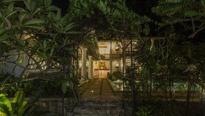 A well-lit entrance with a stone pathway leading to a building surrounded by lush greenery. - Bilin Tree House (Galle)