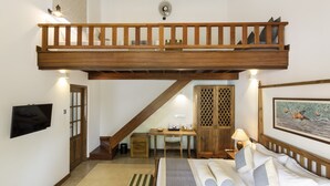 A loft bedroom with a wooden balcony, a desk, and a painting on the wall. - Bilin Tree House (Galle)