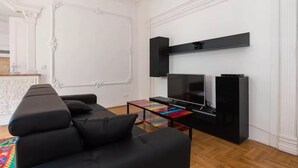 A modern living room with a black leather sofa, a flat-screen TV, and a black entertainment unit.