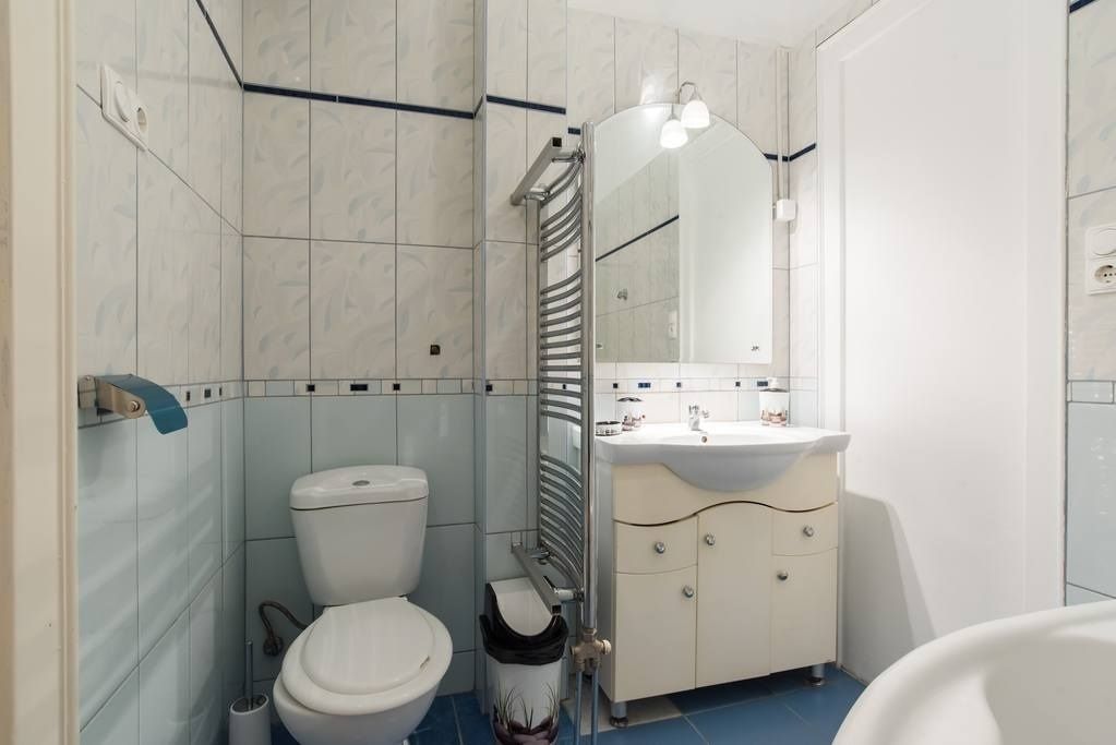 A bathroom with a toilet, sink, and mirror.