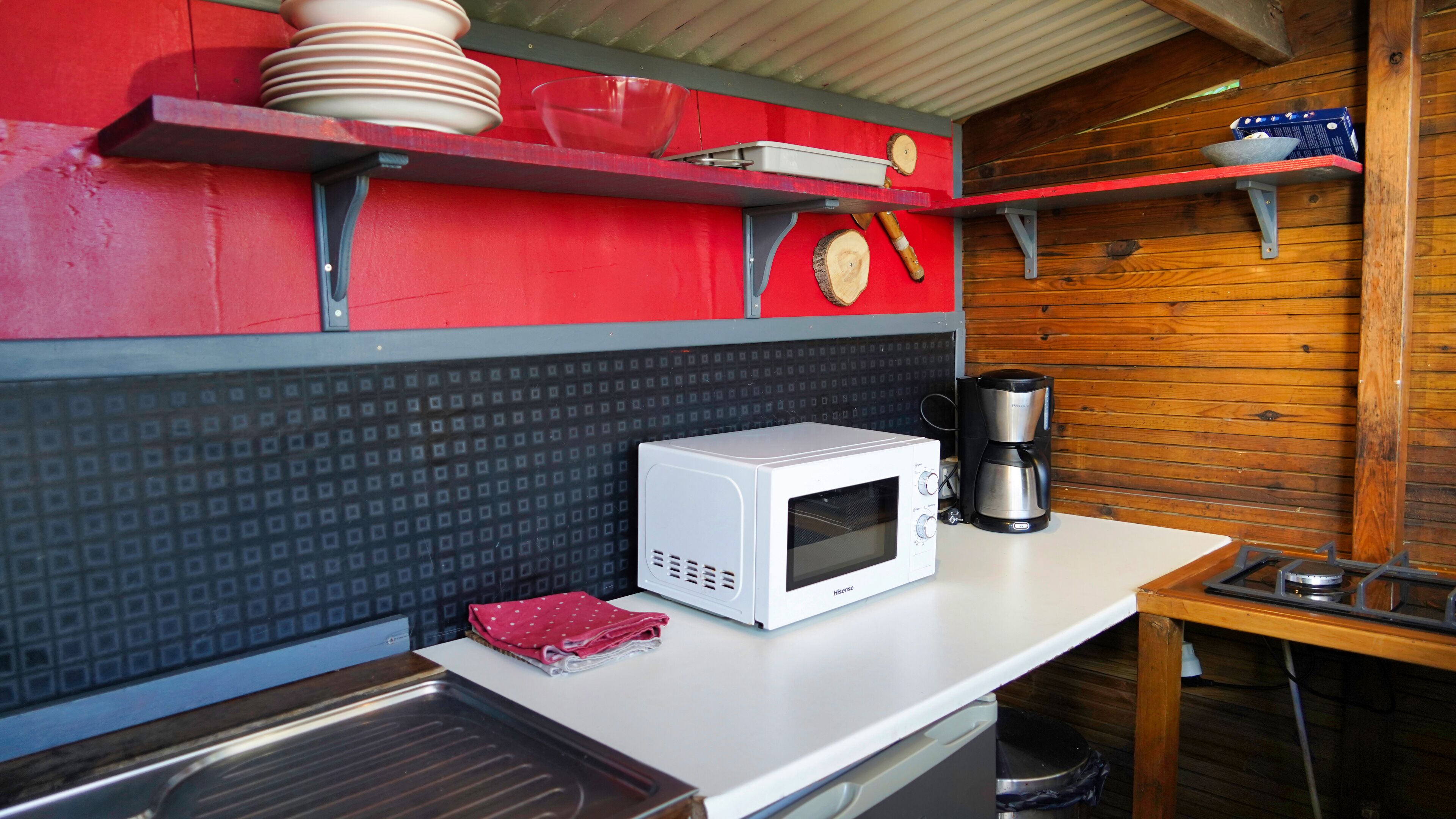A compact kitchen with a microwave, coffee maker, and a sink.