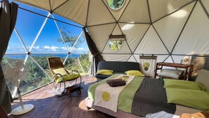 A tented accommodation with a bed, a chair, a small table, and a fan. - Bubble Dome Village- Glamping (Saint-Joseph)