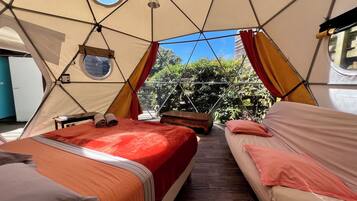 A tented accommodation with two beds, a wooden bench, and a small table.