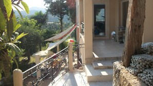 A balcony with a view of a garden and mountains, a wooden railing, and a door leading to an interior space. - Large Provencal house with magnificent views in the heart of a historic village (Fayence)
