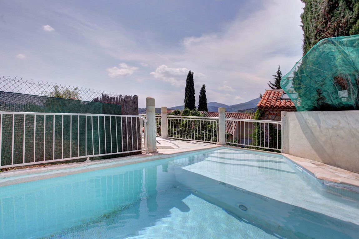 A swimming pool with a view of mountains and a fenced area.