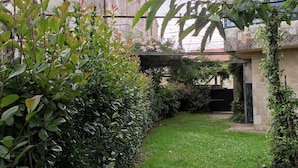 Een weelderige tuin met diverse planten en een stenen gebouw op de achtergrond.