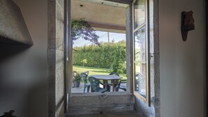 Een stenen trap leidt naar een overdekt terras met een tafel en stoelen.