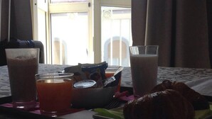 A breakfast tray with croissant, juice, and a coffee cup on a bed with a window view. - B&B Re Ferdinando (Naples)