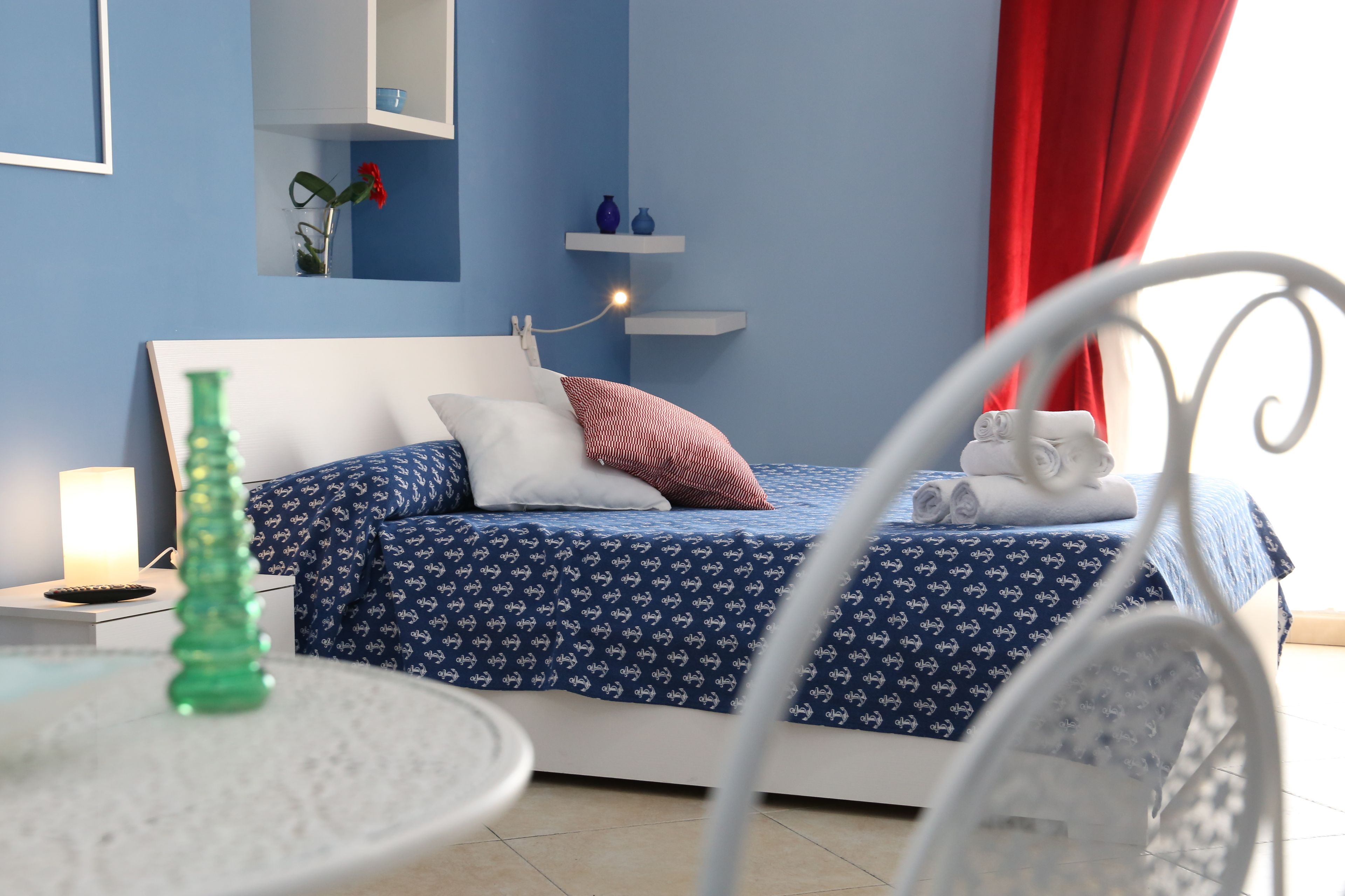Ein ordentlich eingerichtetes Schlafzimmer mit einem Bett, Nachttischen und einem kleinen Tisch mit einer grünen Flasche.