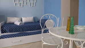 A bedroom with a bed, a white metal chair, and a table with two bottles. - B&B Re Ferdinando (Naples)