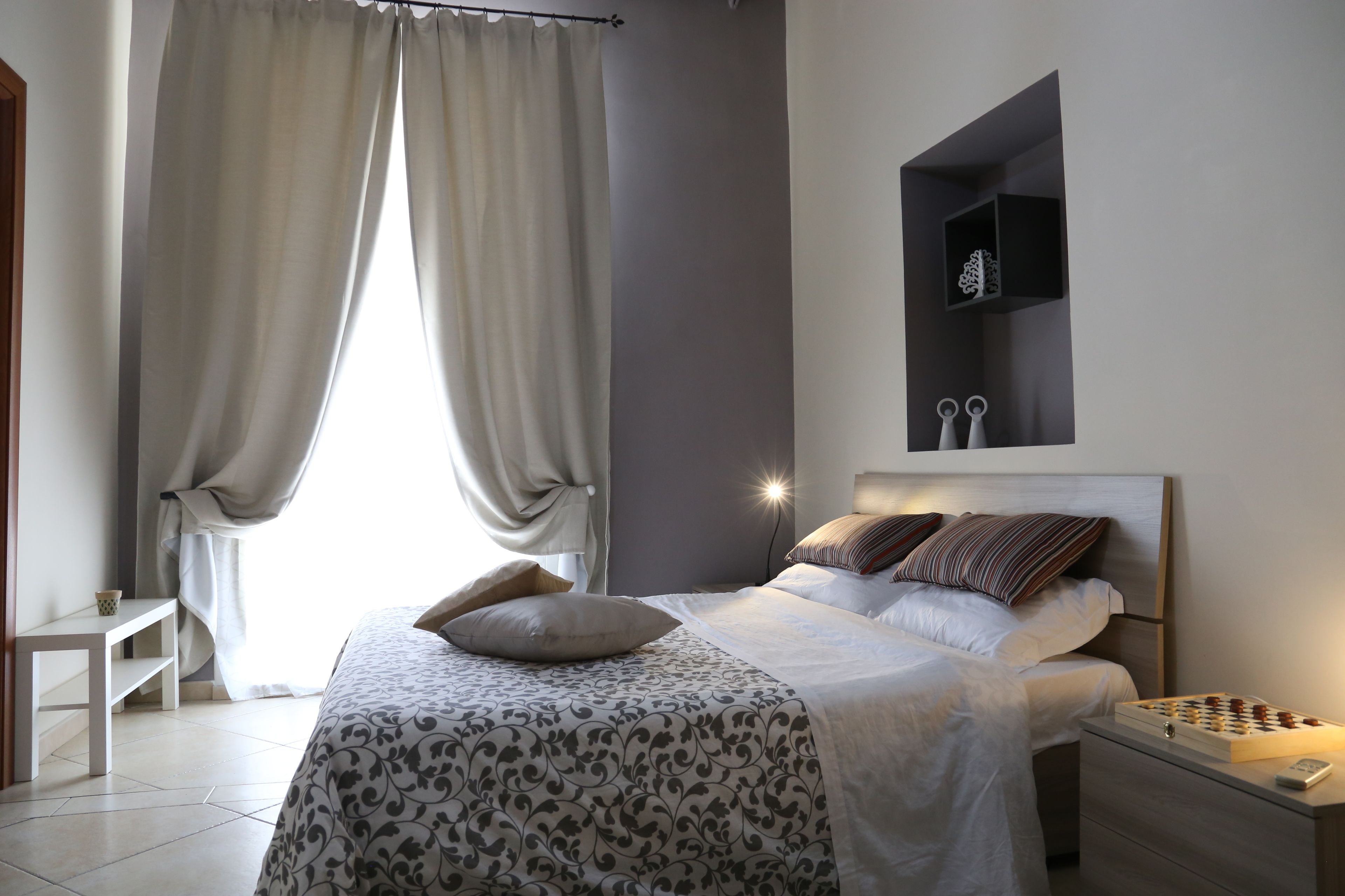 A modern bedroom with a bed, bedside table, and a nightstand with a chessboard.