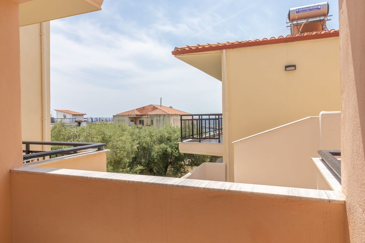 A balcony with a view of a building with a red roof and a satellite dish.