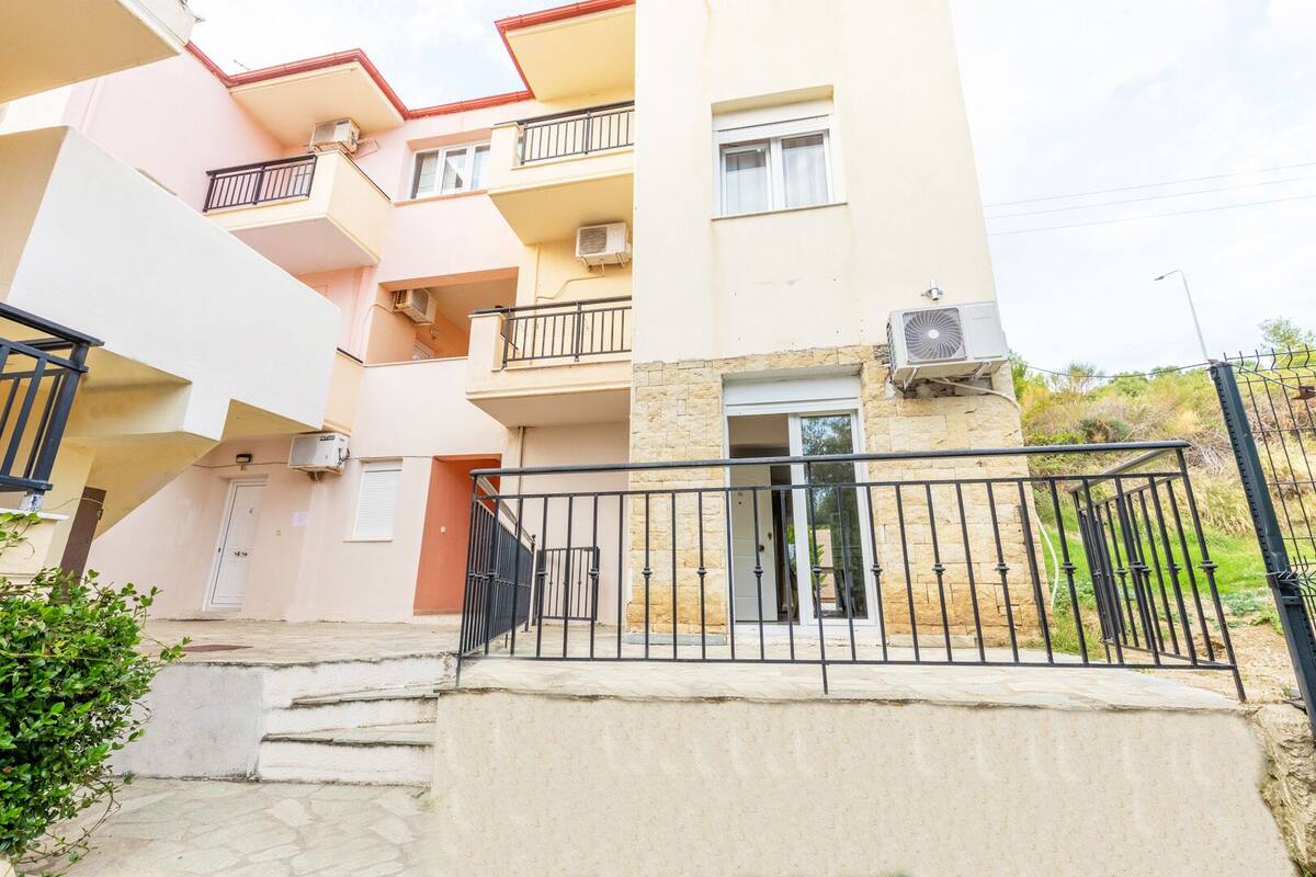 A multi-story residential building with balconies, a gated entrance, and an air conditioning unit on the exterior wall.