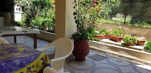 A patio with a table and chairs, surrounded by potted plants and a decorative wall.