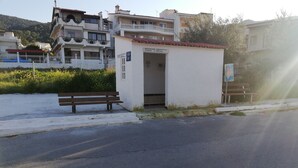 A small white building with a sign indicating it is a public restroom. - Salamina's Apartment (Salamis)