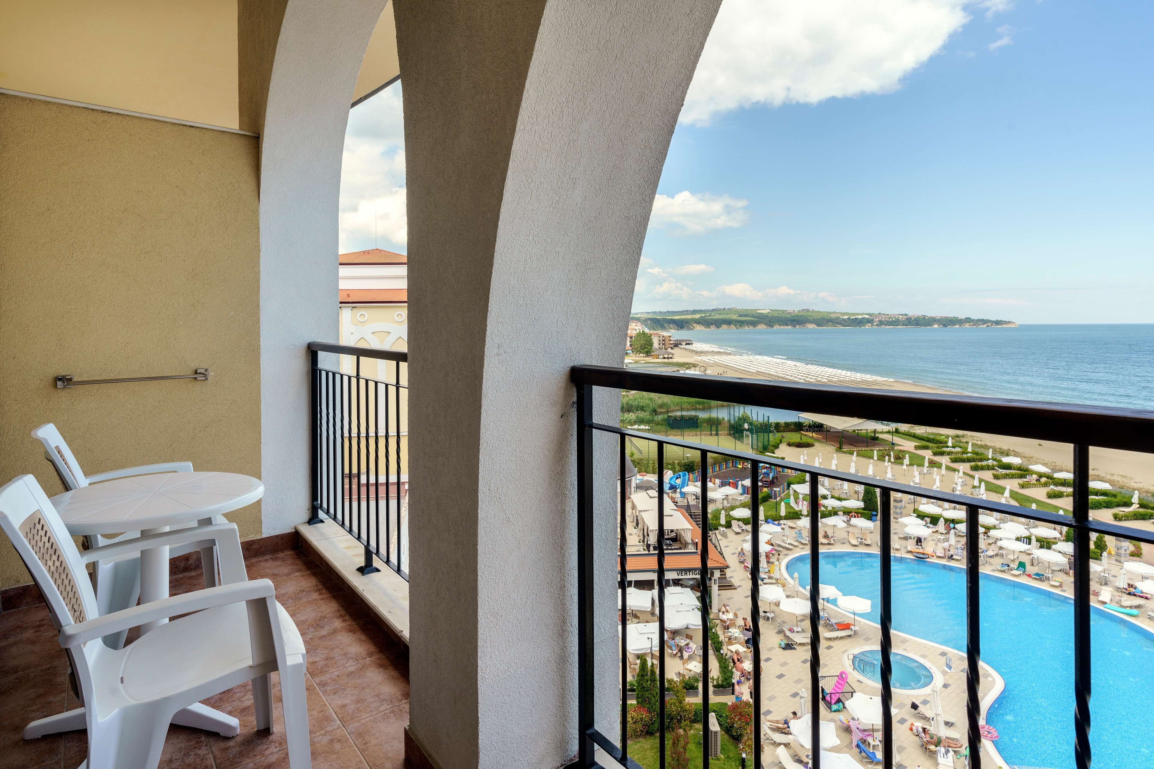 A balcony with a view of a swimming pool and beach.