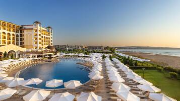 Un complexe hôtelier doté d’une grande piscine, de chaises longues et offrant une vue sur la plage.