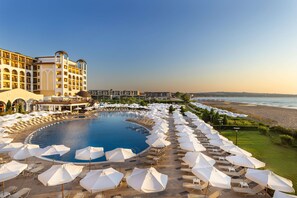 A resort with a large pool, sun loungers, and a beach view.