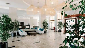 A spacious lobby with modern furniture, large windows, and multiple hanging light fixtures. -  Alua Helios Bay - All Inclusive (Obzor)