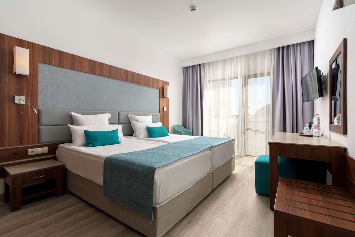 A modern hotel room with a large bed, a desk, and a TV.