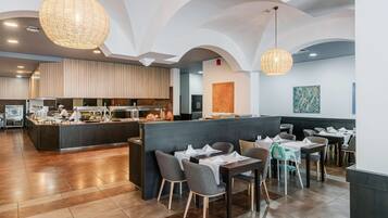 Um restaurante moderno com balcão central, área de refeições com mesas e cadeiras, e cozinha ao fundo.
