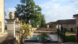 Ein Innenhof mit Pool, weißen Metallstühlen und einem Tisch.
