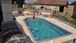 Ein rechteckiger Pool, umgeben von Steinmauern und einer gefliesten Terrasse.