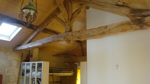 Ein rustikaler Raum mit sichtbaren Holzbalken, einem Etagenbett, einem weißen Schrank und einem Oberlicht.