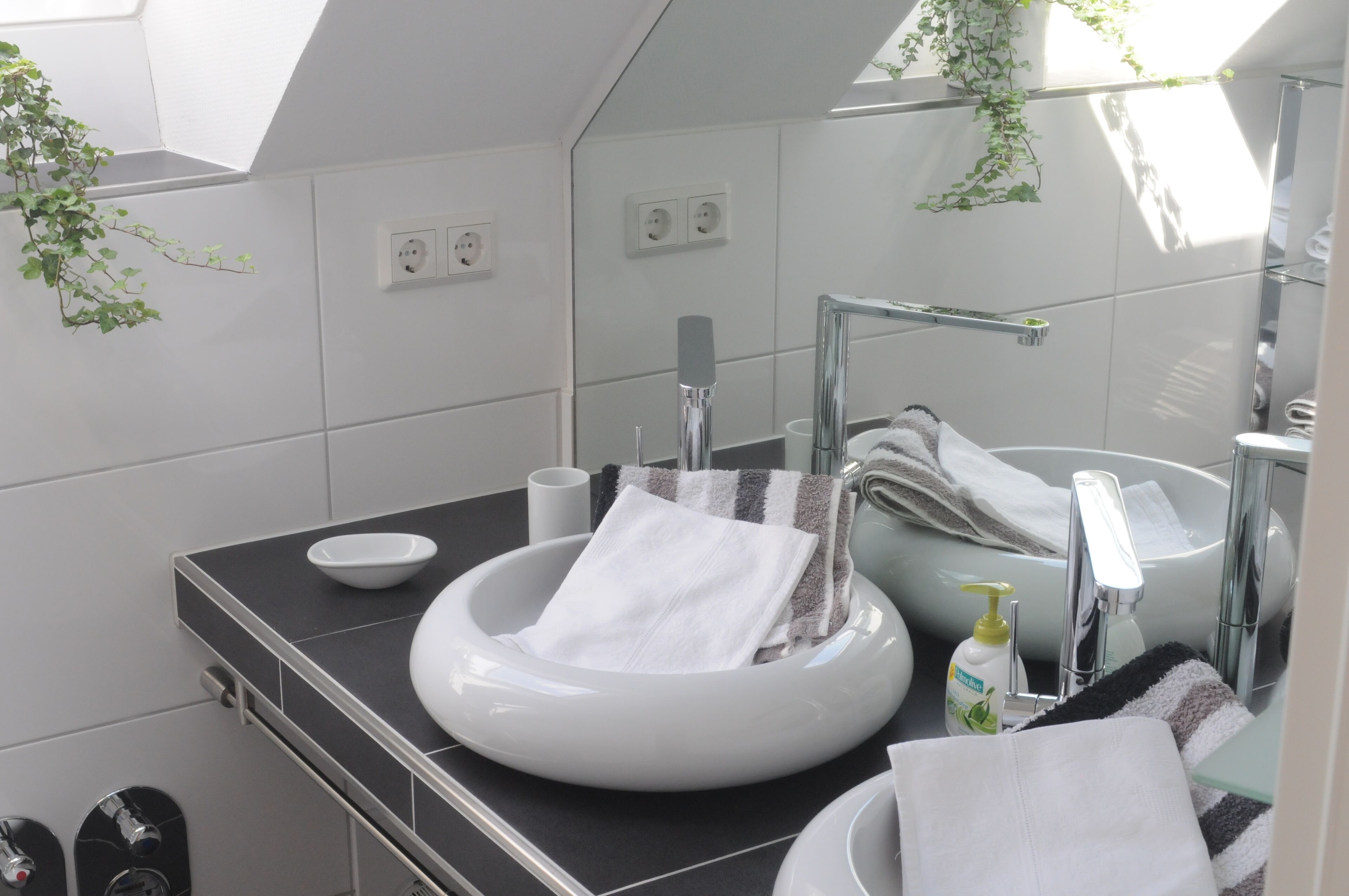 Un baño moderno con un lavamanos redondo, un espejo y un perchero para toallas.