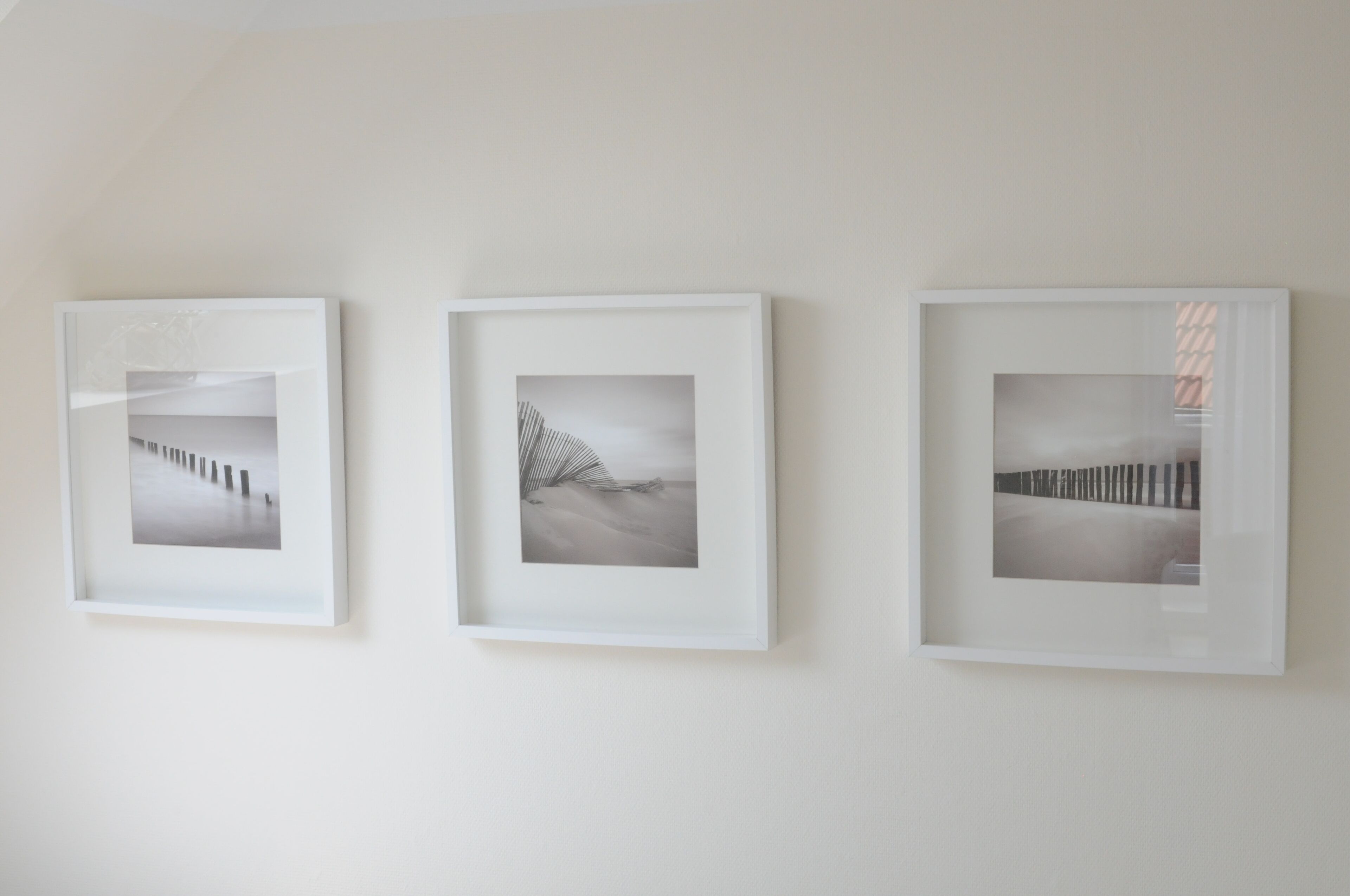 Trois photographies encadrées accrochées à un mur uni.