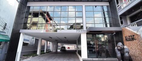 Un edificio moderno con vestíbulo cubierto, ventanas amplias y una estatua de gorila.