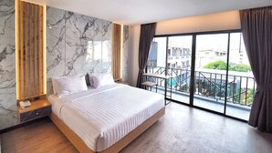 Ein modernes Hotelzimmer mit einem großen Bett, Marmorwand, Holzelementen und einem Balkon mit Blick auf die Stadt.