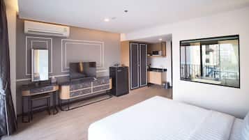 Una habitación de hotel moderna con una cama grande, un escritorio con silla, televisión integrada, microondas y armario.