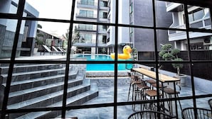 Ein modernes Gebäude mit Pool, Sitzgelegenheiten im Freien und Blick auf eine Wohngegend.