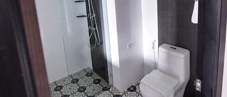 Un baño moderno con ducha, inodoro y baldosas de suelo estampadas.