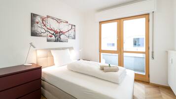 Una camera da letto con un letto, una cassettiera, un comodino, una finestra e un'opera d'arte appesa al muro.