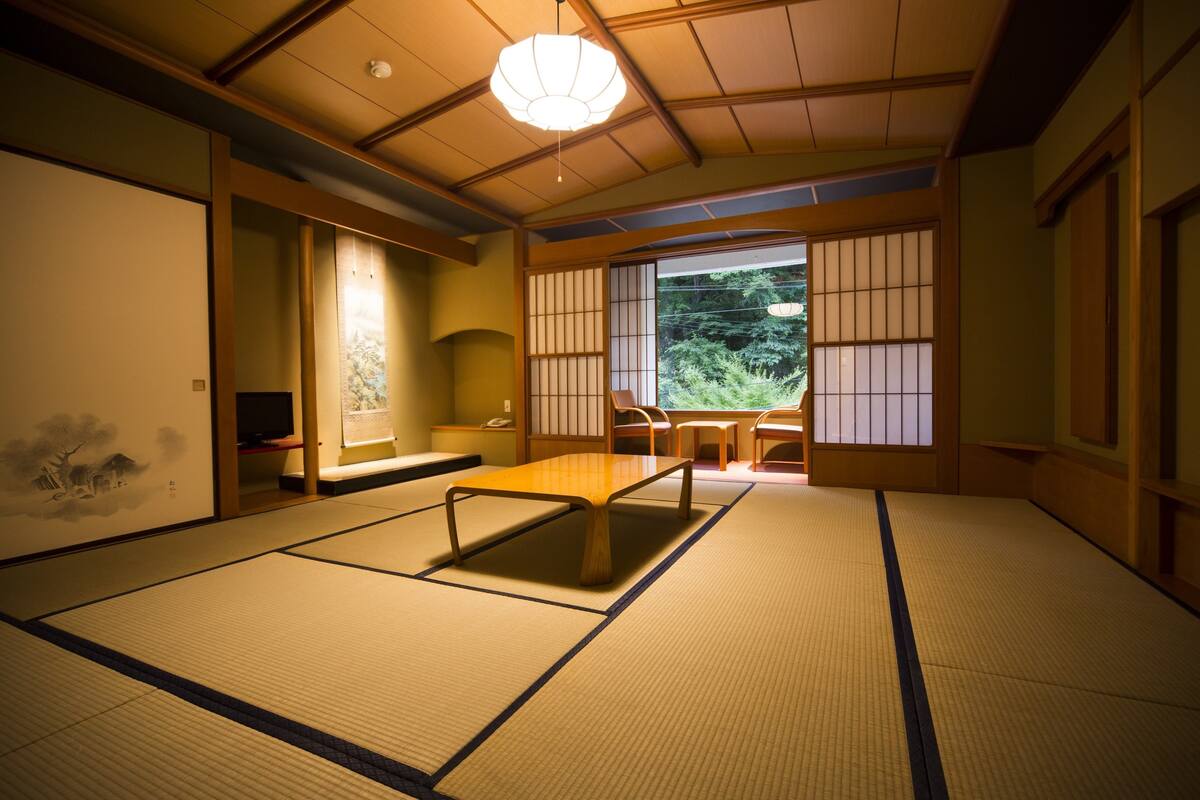 Une pièce de style japonais traditionnel, avec un sol recouvert de tatamis, une table basse et des portes coulissantes.