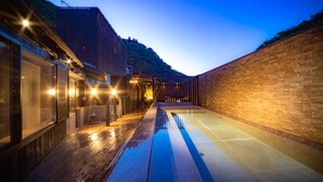 Un espace piscine extérieur moderne, doté d’une terrasse en bois, d’une structure en verre et d’un mur en briques.