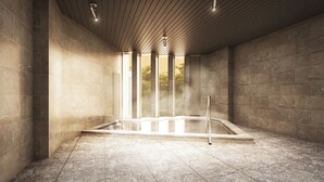Un espace spa moderne doté d’un sol carrelé en pierre, d’un plafond en bois et d’un jacuzzi entouré de parois en verre.
