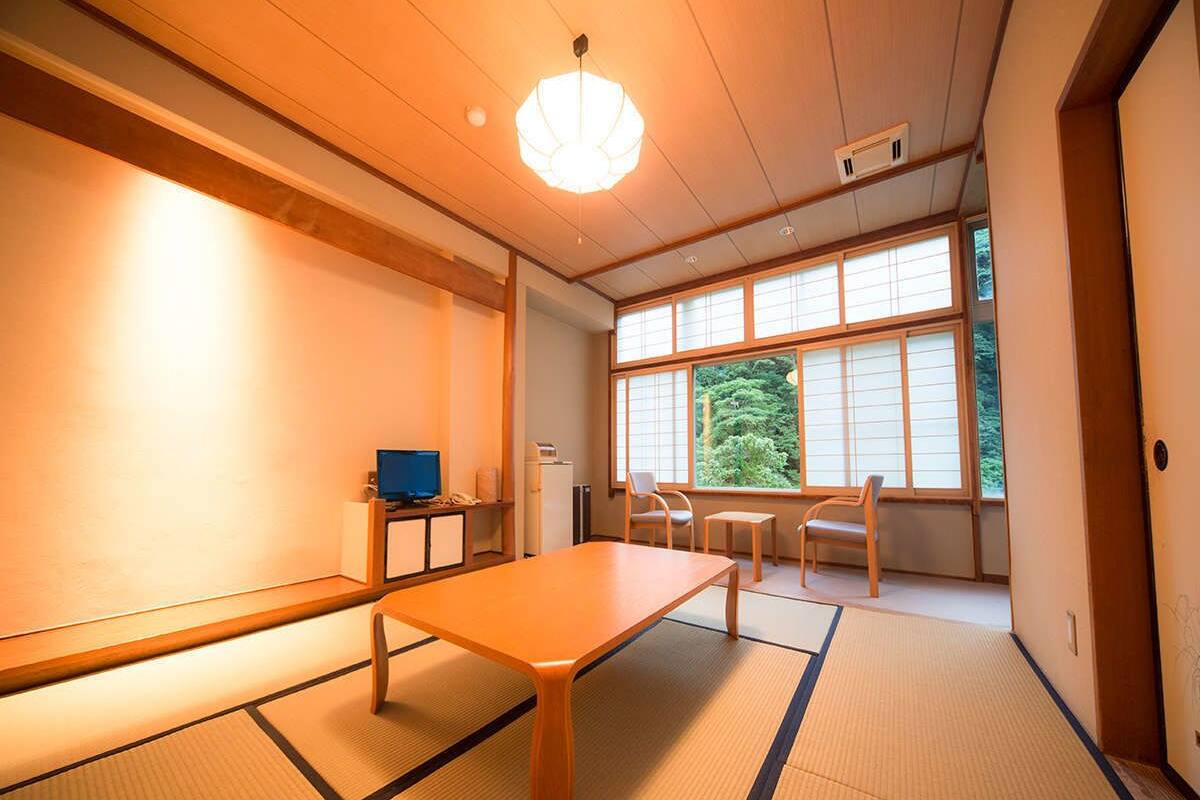 Une pièce de style japonais traditionnel, avec un sol recouvert de tatamis, une table basse et des portes coulissantes.