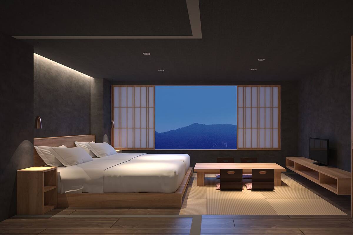 Une chambre moderne avec un grand lit, une télévision, un bureau en bois et une vue sur les montagnes par une grande fenêtre.