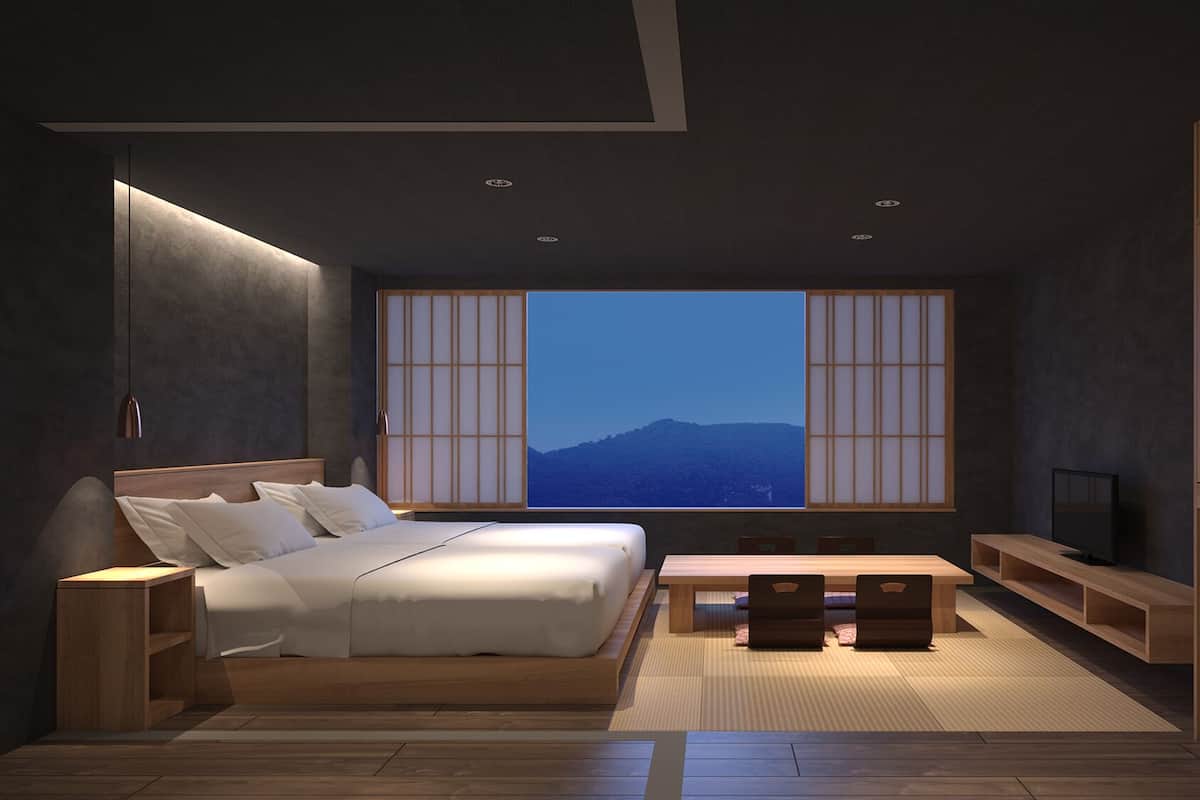 Ein modernes Schlafzimmer mit einem großen Bett, einem Fernseher, einem Holztisch und Bergblick durch ein großes Fenster.