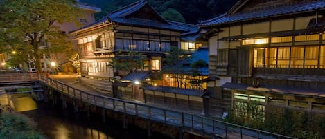 Un complejo arquitectónico japonés tradicional con varias construcciones unidas por un puente sobre un canal.