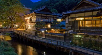 Un complejo arquitectónico japonés tradicional con varias construcciones unidas por un puente sobre un canal.