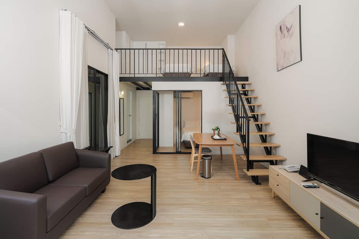 A modern living room with a sofa, a coffee table, a TV, and a staircase leading to an upper level.