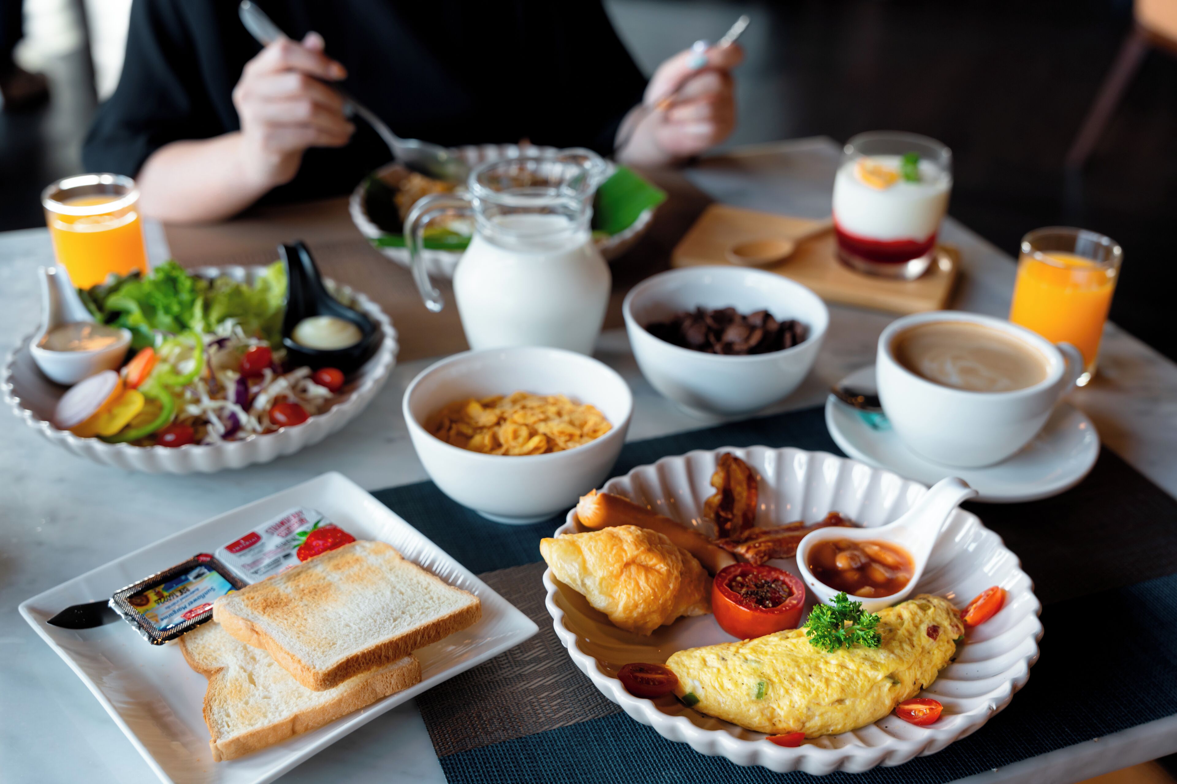 Une table de petit-déjeuner avec différents plats, notamment des toasts, des œufs et une salade.