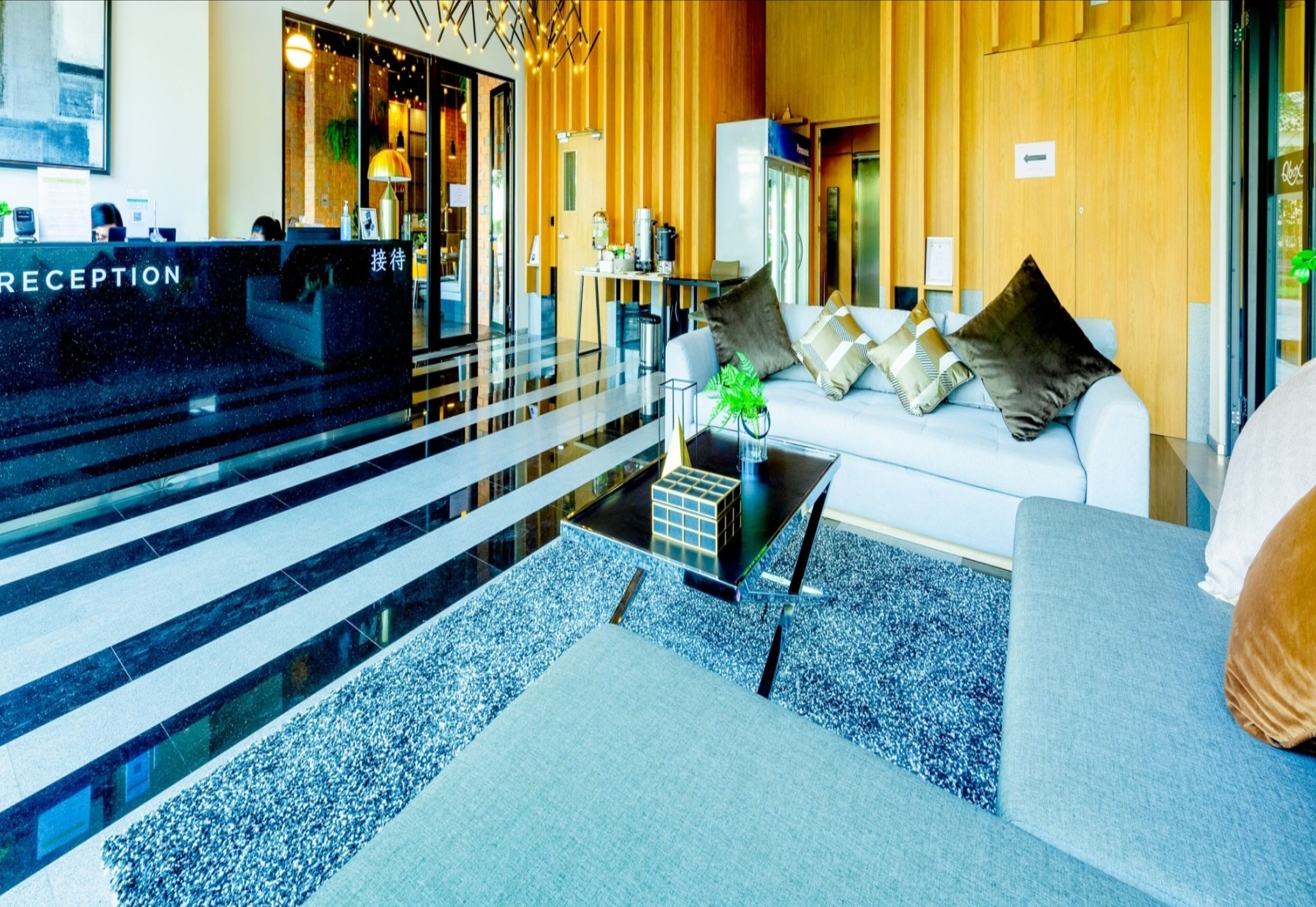 A reception area with a reception desk, a sofa with cushions, a small table with a plant, and a coffee machine.