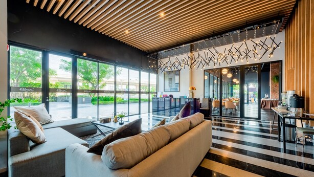 Een moderne hotellobby met een receptiebalie, zithoek en grote ramen met uitzicht op de omgeving.