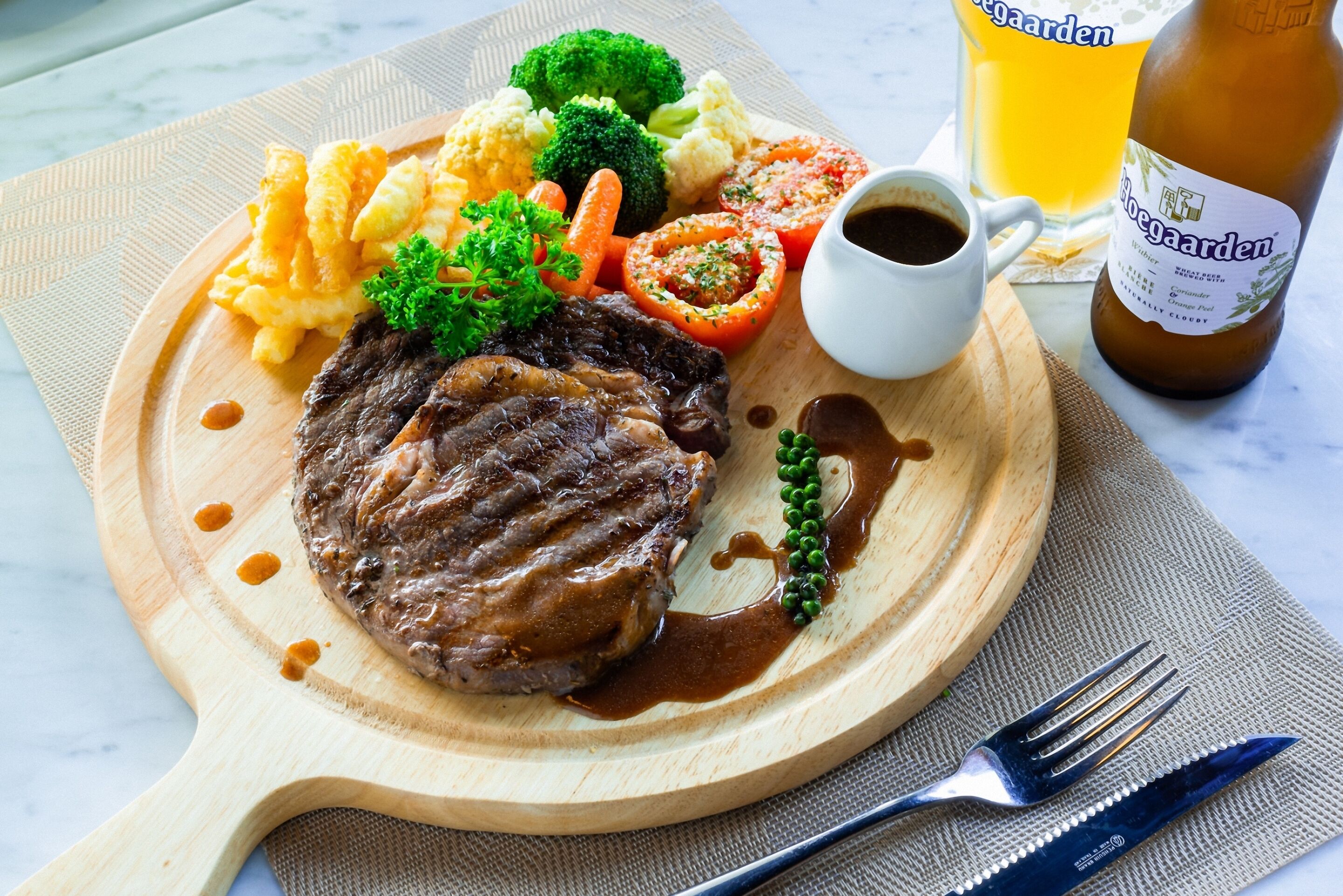A plate with steak, vegetables, and a beer bottle.